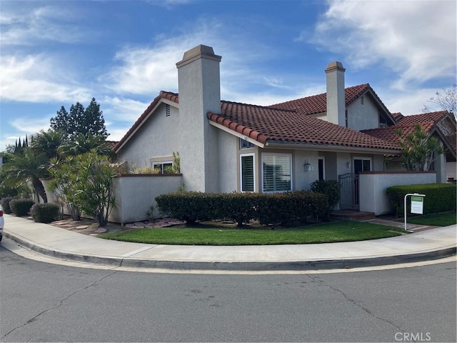 view of front of home featuring stucco siding, a chimney, and a tiled roof