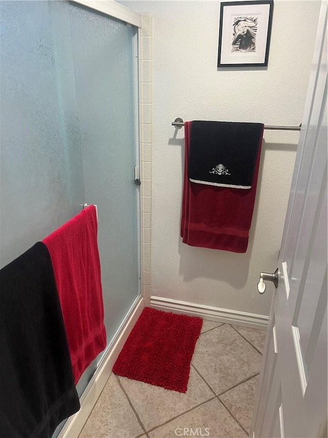 bathroom with baseboards, a shower stall, and tile patterned floors