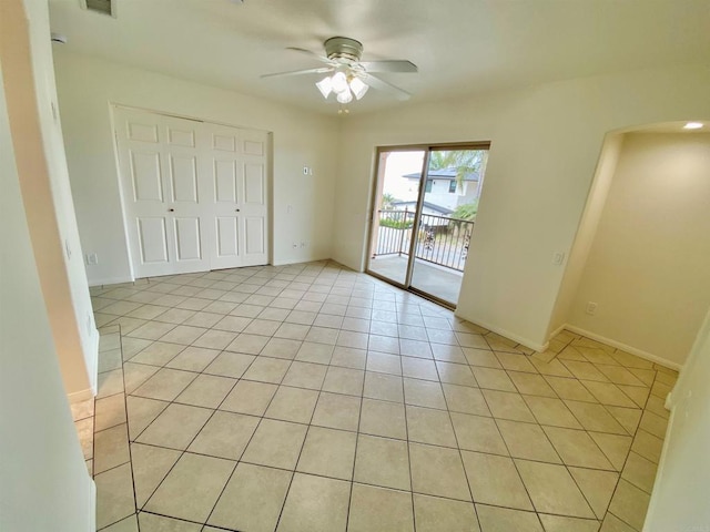 unfurnished bedroom with a ceiling fan, a closet, light tile patterned floors, arched walkways, and access to exterior