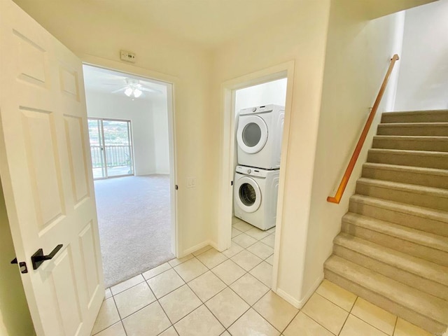laundry room with stacked washing maching and dryer, light tile patterned floors, light carpet, baseboards, and laundry area