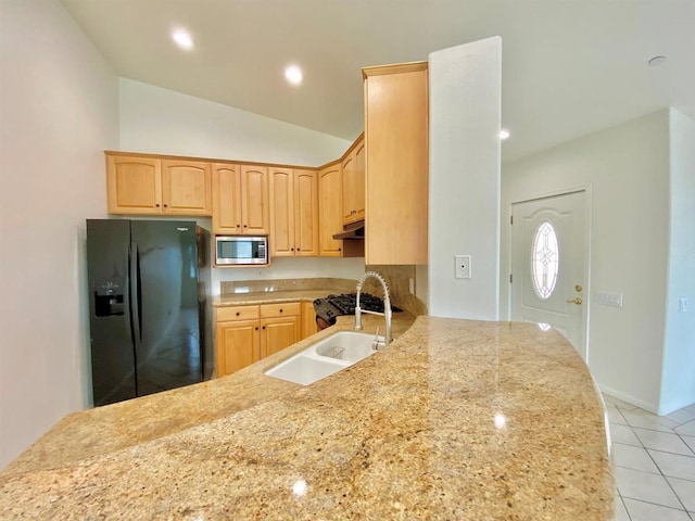 kitchen featuring stainless steel microwave, a sink, black fridge, and light brown cabinets