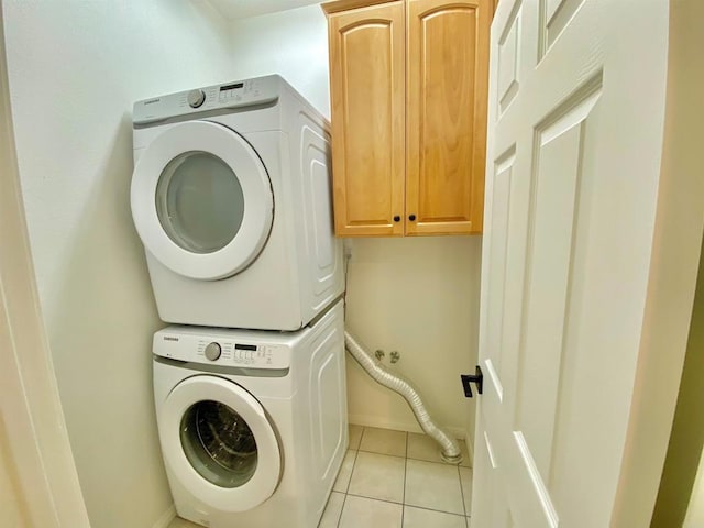 laundry room featuring stacked washer / drying machine, baseboards, light tile patterned floors, and cabinet space