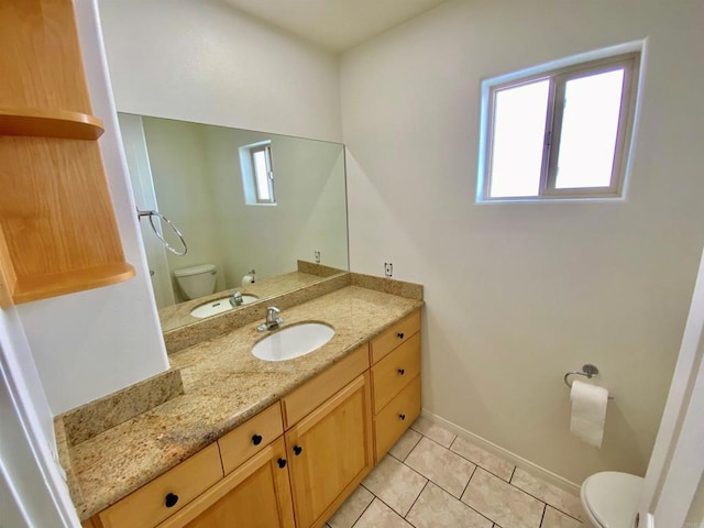 bathroom with toilet, vanity, tile patterned floors, and baseboards