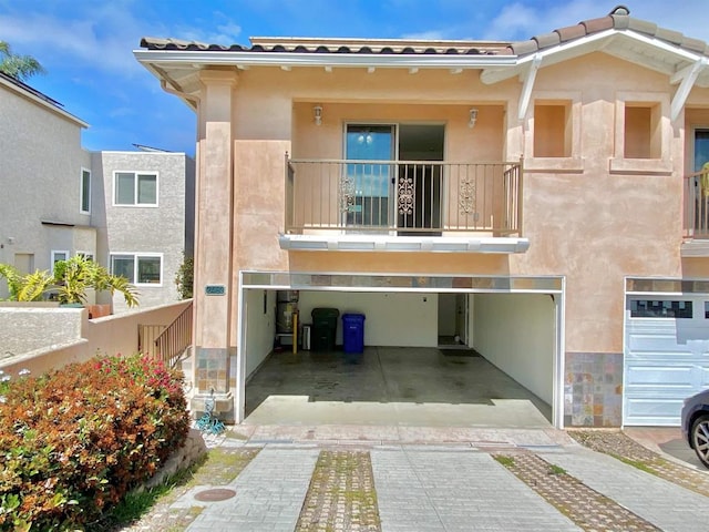 view of front of home featuring driveway, a garage, stucco siding, and a balcony