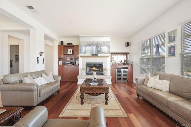 living area with dark wood-style floors, wine cooler, visible vents, and a tiled fireplace