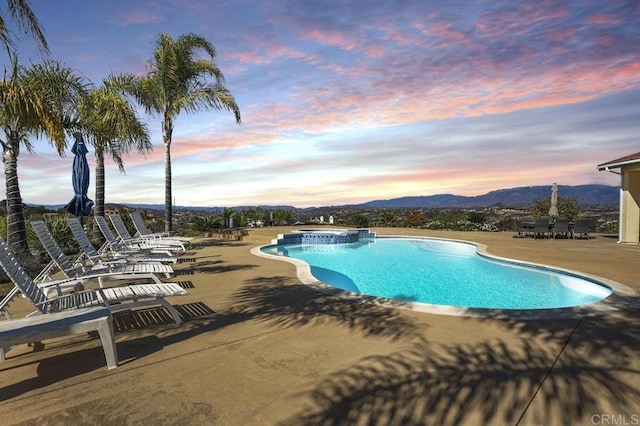 outdoor pool featuring an in ground hot tub, a patio area, and a mountain view