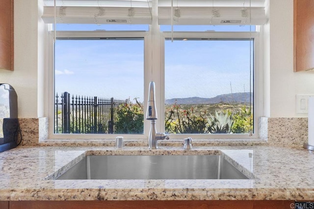 interior details featuring a sink, a mountain view, and light stone countertops