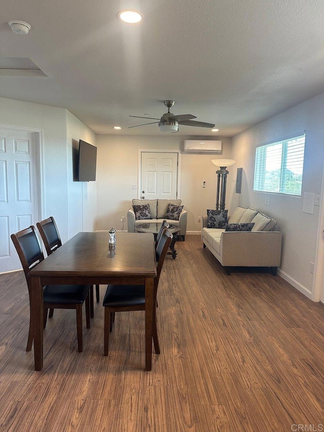 dining space with baseboards, a ceiling fan, dark wood-style floors, a textured ceiling, and a wall mounted AC