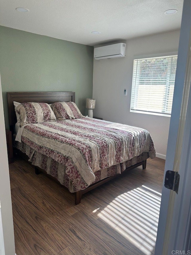 bedroom with a textured ceiling, dark wood-style flooring, and an AC wall unit