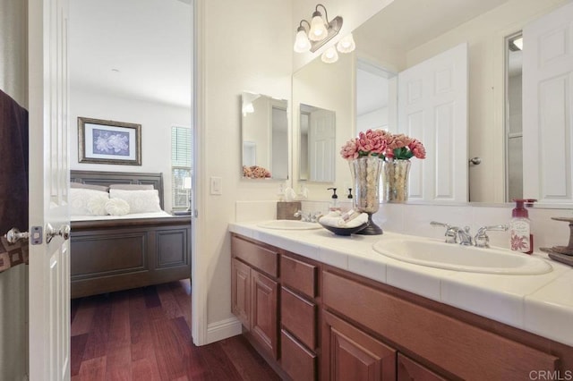 bathroom with double vanity, a sink, ensuite bath, and wood finished floors