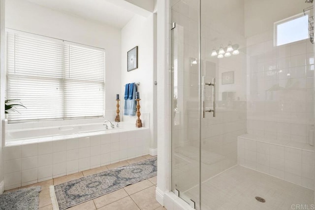 bathroom with a stall shower, a bath, and tile patterned floors