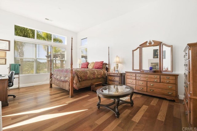 bedroom with visible vents, baseboards, and wood finished floors