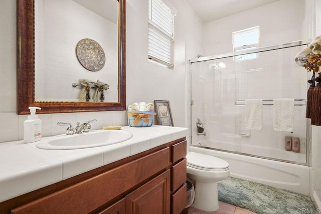 bathroom with shower / bath combination with glass door, vanity, toilet, and tile patterned floors