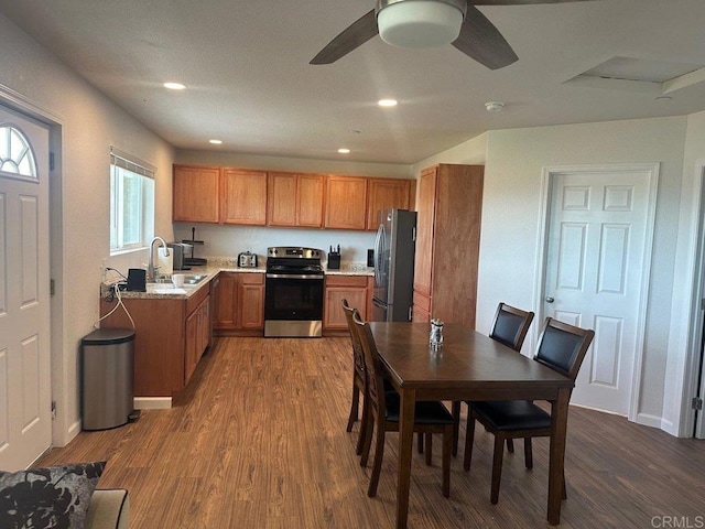 kitchen featuring stainless steel appliances, brown cabinets, a sink, and wood finished floors