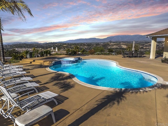 view of pool featuring a pool with connected hot tub, a patio area, and a mountain view