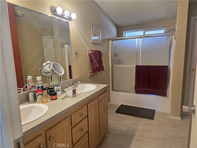 full bathroom with double vanity, enclosed tub / shower combo, and a sink