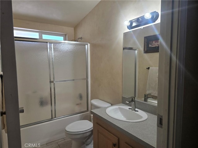 full bathroom featuring shower / bath combination with glass door, tile patterned flooring, vanity, and toilet