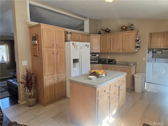 kitchen featuring white refrigerator with ice dispenser, a kitchen island, light countertops, independent washer and dryer, and light brown cabinetry