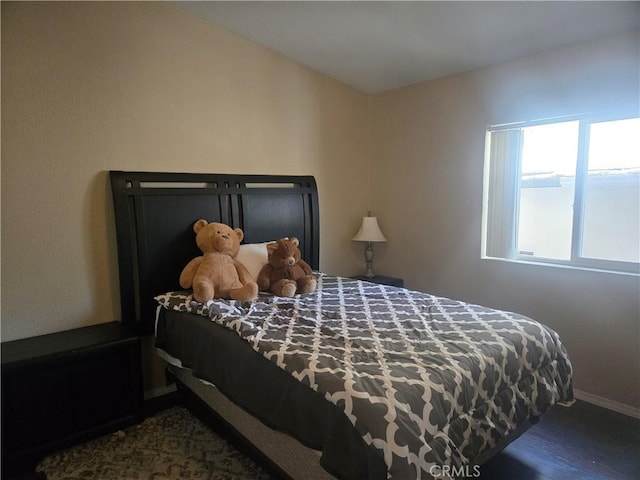 bedroom with baseboards and dark wood-type flooring