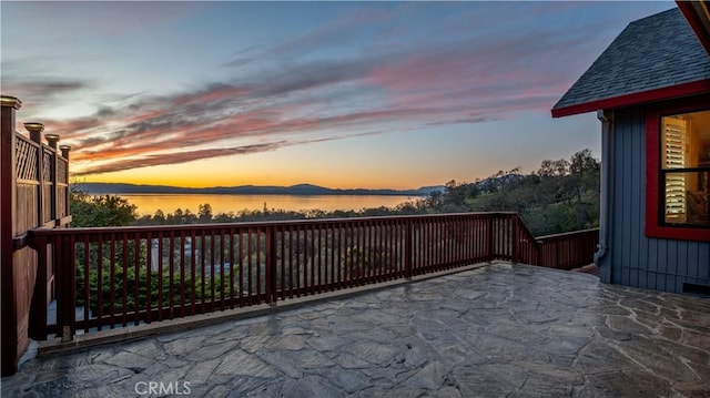 patio terrace at dusk featuring a water view