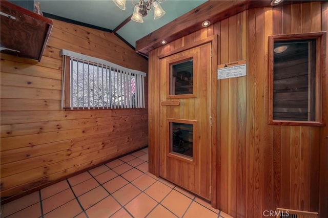 kitchen with lofted ceiling, wooden walls, and light tile patterned flooring