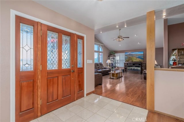 foyer featuring a ceiling fan, vaulted ceiling, and light tile patterned floors