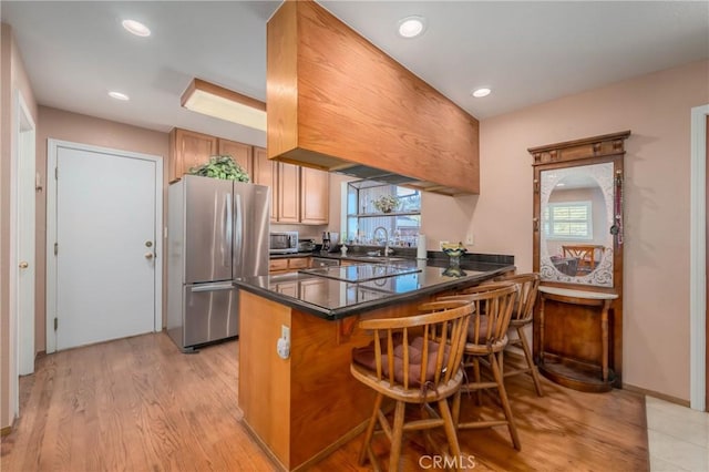 kitchen featuring plenty of natural light, stainless steel appliances, a peninsula, and dark countertops