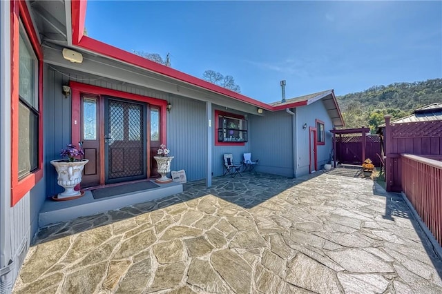 view of exterior entry featuring a patio area and fence