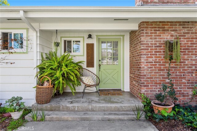 view of exterior entry featuring brick siding and visible vents