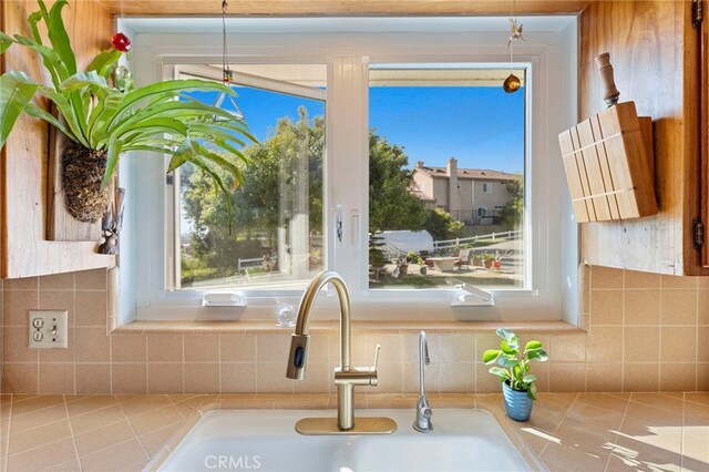 room details with decorative backsplash, light countertops, decorative light fixtures, and a sink