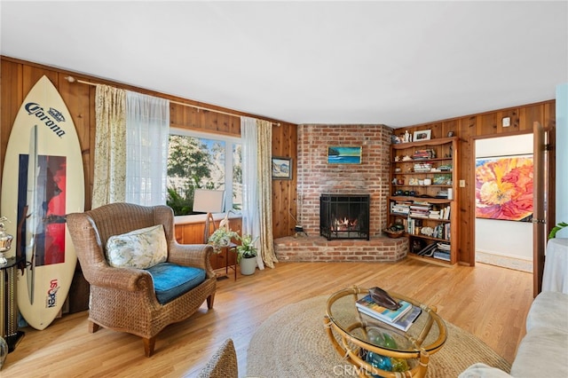 living room with light wood-style floors, a fireplace, and wood walls