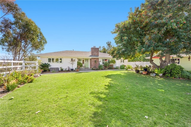 rear view of property with a chimney, fence, and a lawn