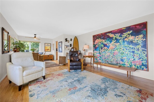 living room featuring wood finished floors, baseboards, and ceiling fan