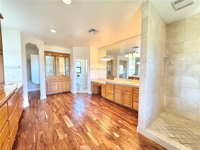 full bathroom with a sink, toilet, wood finished floors, and visible vents