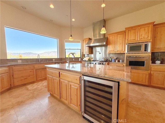 kitchen with beverage cooler, an island with sink, wall chimney exhaust hood, appliances with stainless steel finishes, and a mountain view