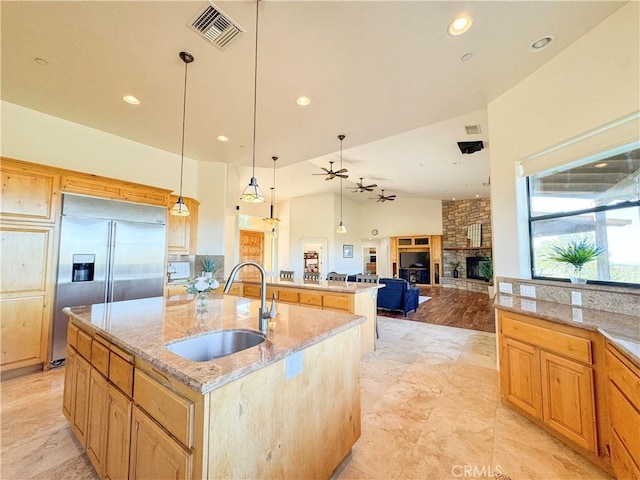 kitchen featuring a kitchen island with sink, a sink, visible vents, open floor plan, and pendant lighting