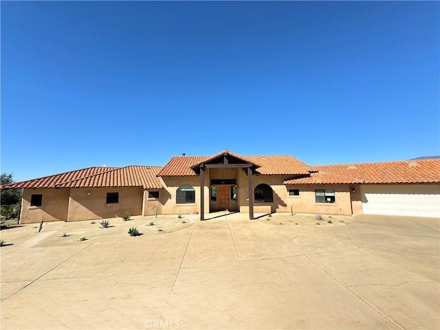 mediterranean / spanish-style home with stucco siding, concrete driveway, and a tiled roof