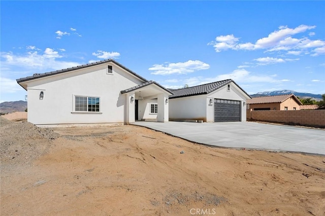 view of front of home featuring a garage, a tile roof, concrete driveway, and stucco siding