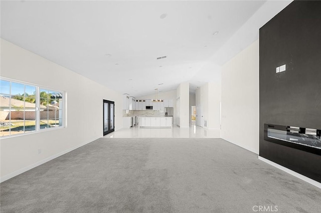 unfurnished living room with lofted ceiling, light carpet, visible vents, and baseboards