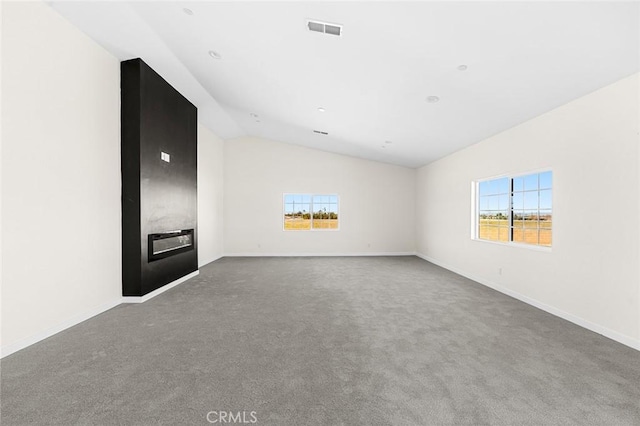 unfurnished room featuring carpet floors, visible vents, vaulted ceiling, and a wealth of natural light