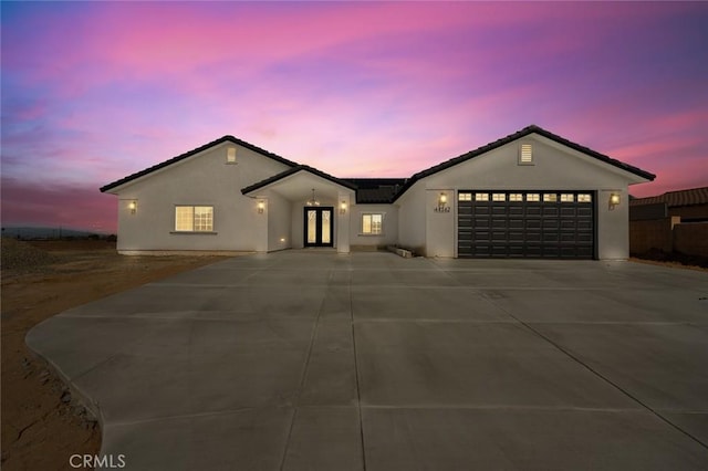 single story home featuring a garage, driveway, and stucco siding