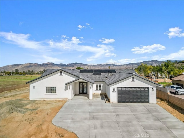 single story home with stucco siding, a tile roof, a mountain view, and roof mounted solar panels