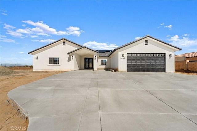 view of front of home with an attached garage, a tiled roof, concrete driveway, and stucco siding