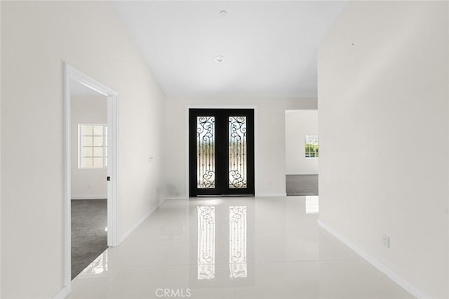 foyer with light tile patterned flooring, baseboards, and french doors