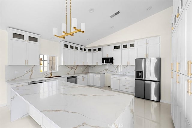 kitchen featuring hanging light fixtures, appliances with stainless steel finishes, a sink, and glass insert cabinets