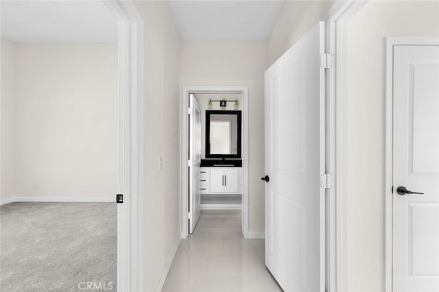 hallway featuring light carpet and baseboards