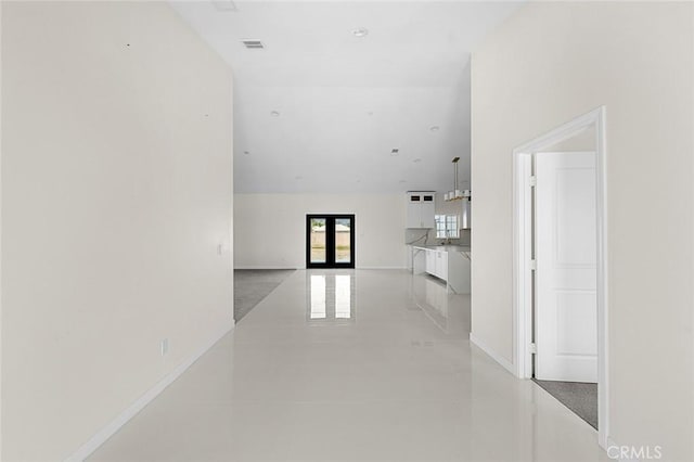 interior space with a high ceiling, french doors, visible vents, and baseboards