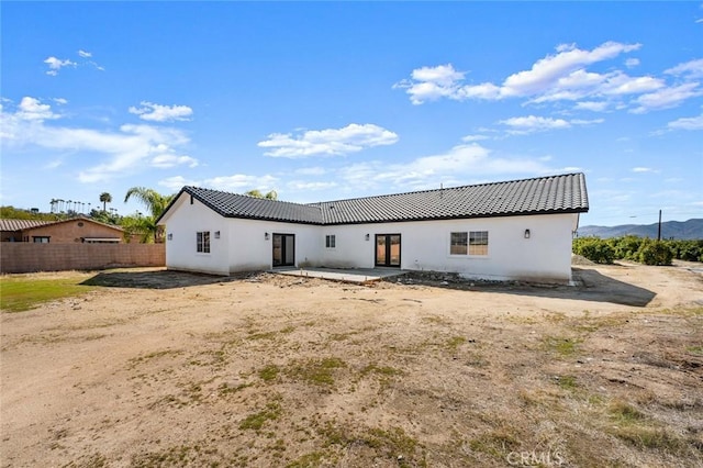 back of property featuring stucco siding, fence, and a tiled roof