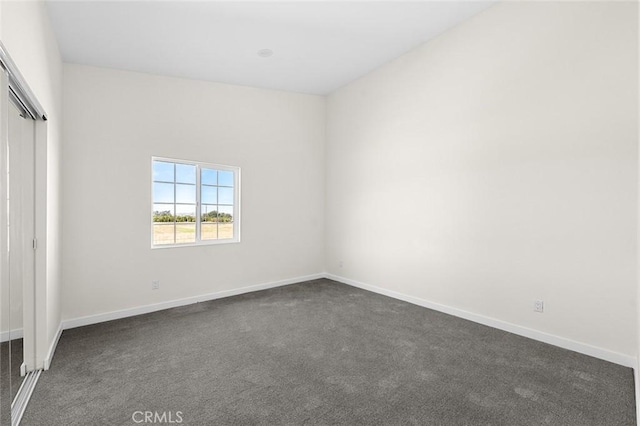 unfurnished bedroom featuring a closet, dark carpet, and baseboards