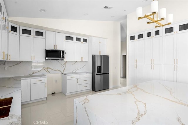 kitchen featuring glass insert cabinets, stainless steel fridge, decorative light fixtures, and white cabinetry